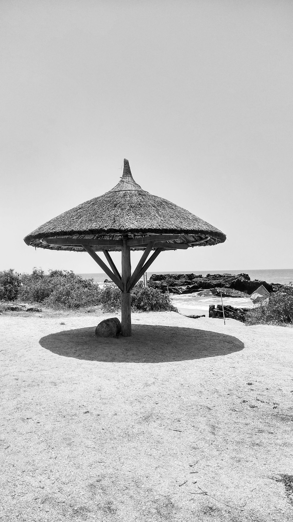 a black and white photo of an umbrella on the beach