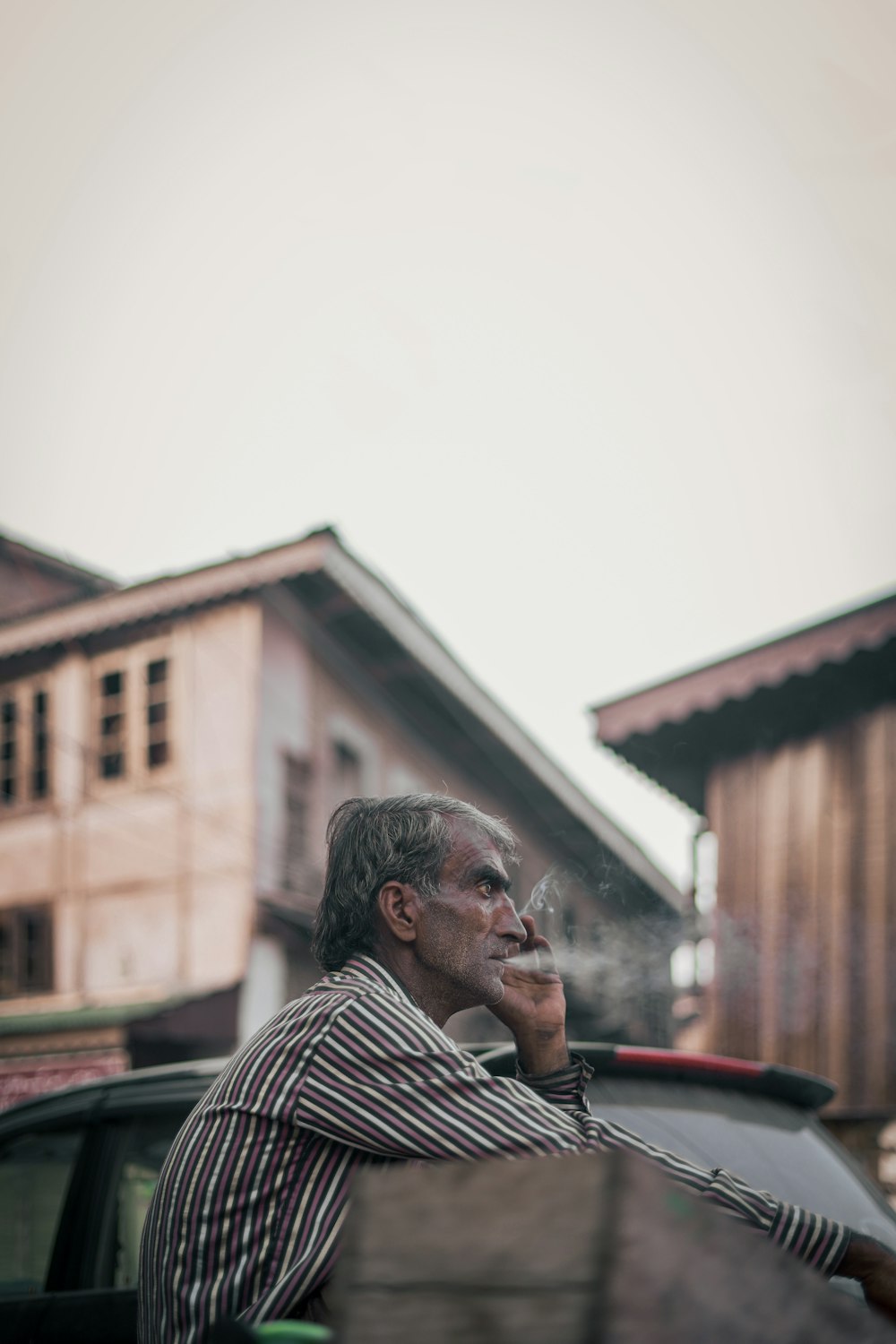 a man sitting on the back of a car smoking a cigarette