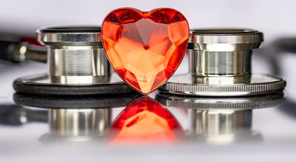 a heart shaped orange diamond sitting on top of a stethoscope