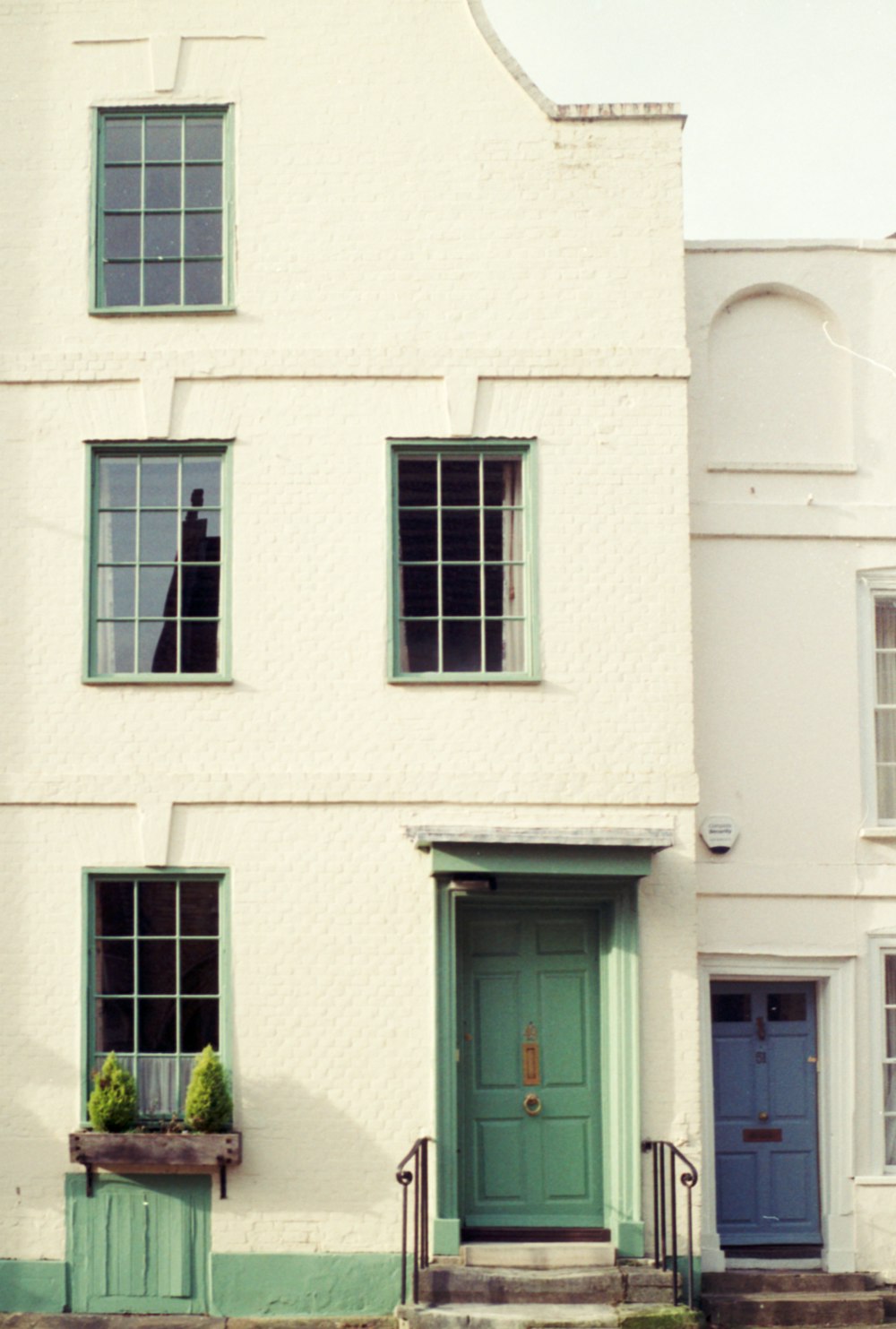 Ein weißes Haus mit grüner Tür und Fenstern