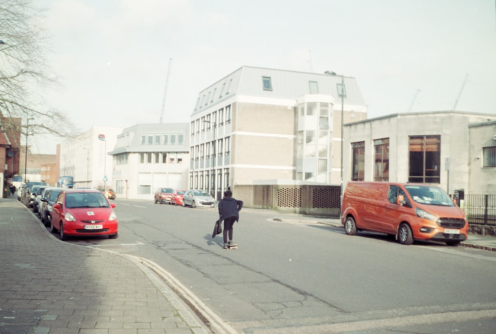 a man riding a skateboard down a street next to parked cars