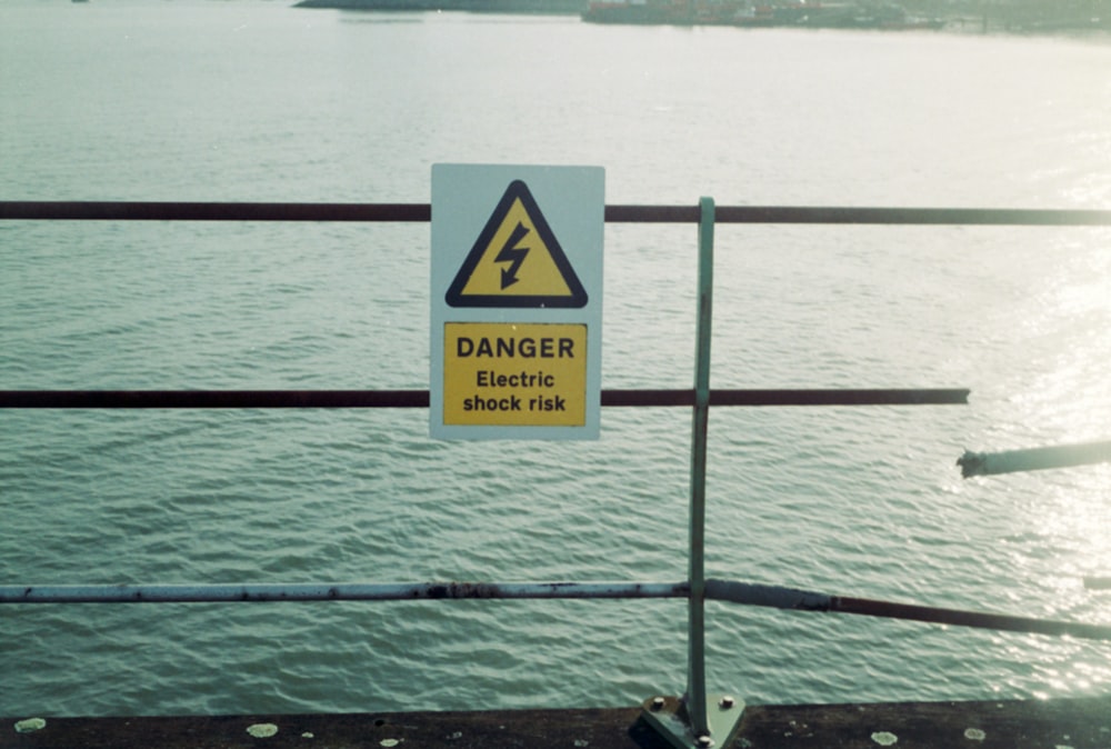 a danger sign on a railing overlooking a body of water