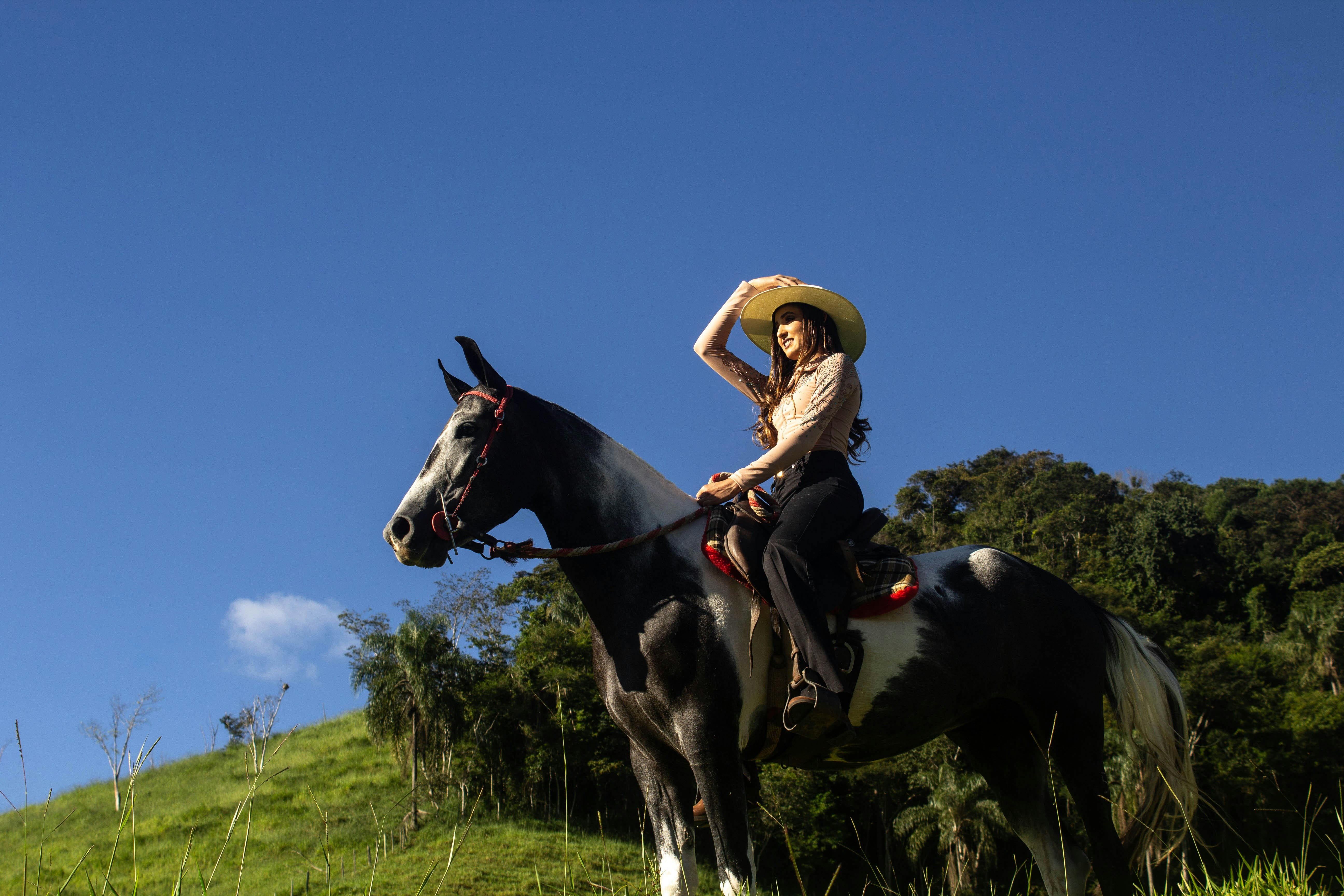 a woman in a straw hat is riding a horse