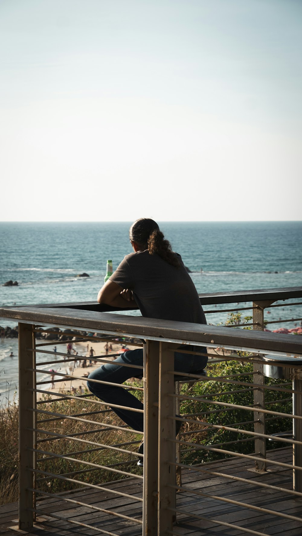 a woman sitting on a railing looking out at the ocean