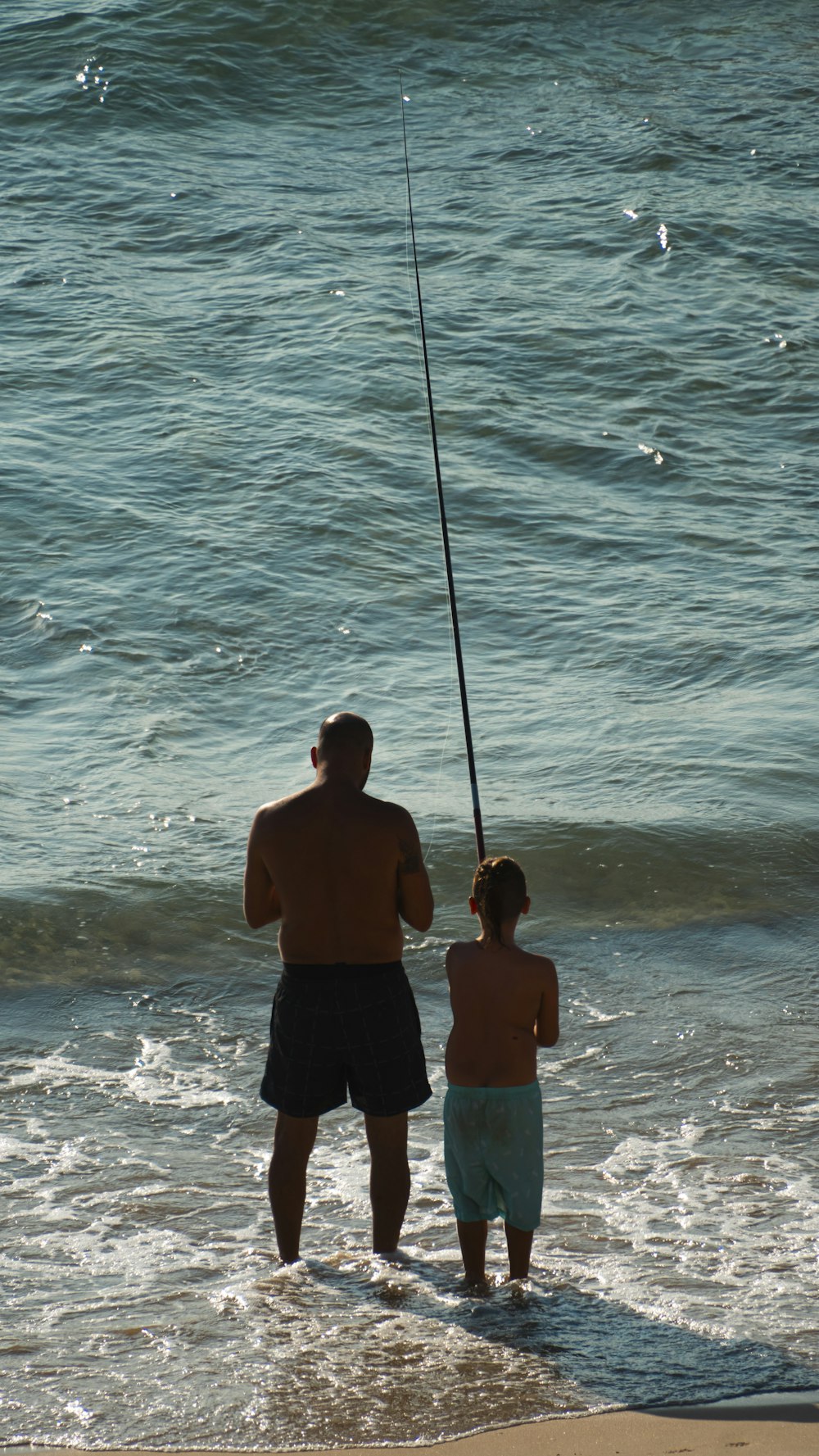 a man and a little girl fishing in the ocean