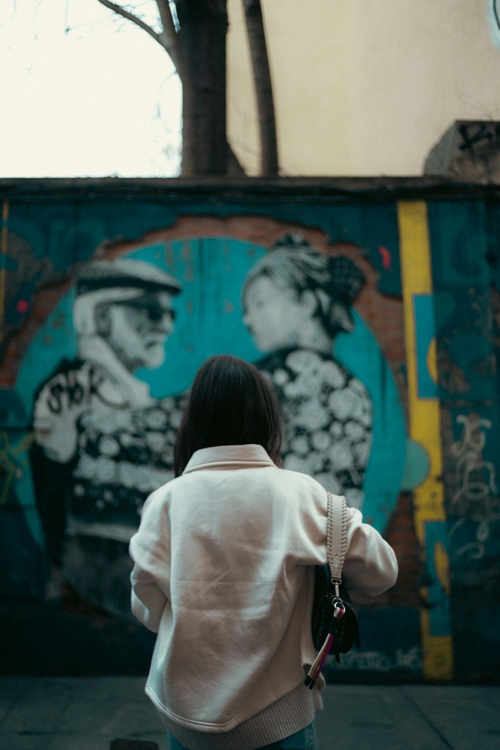 a woman standing in front of a graffiti covered wall