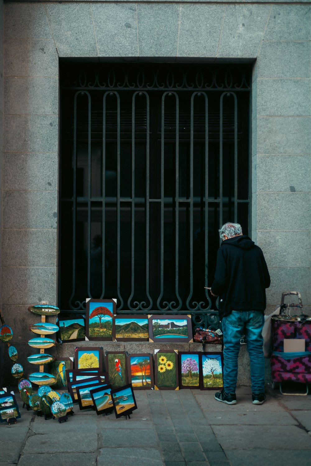 a man standing next to a bunch of paintings