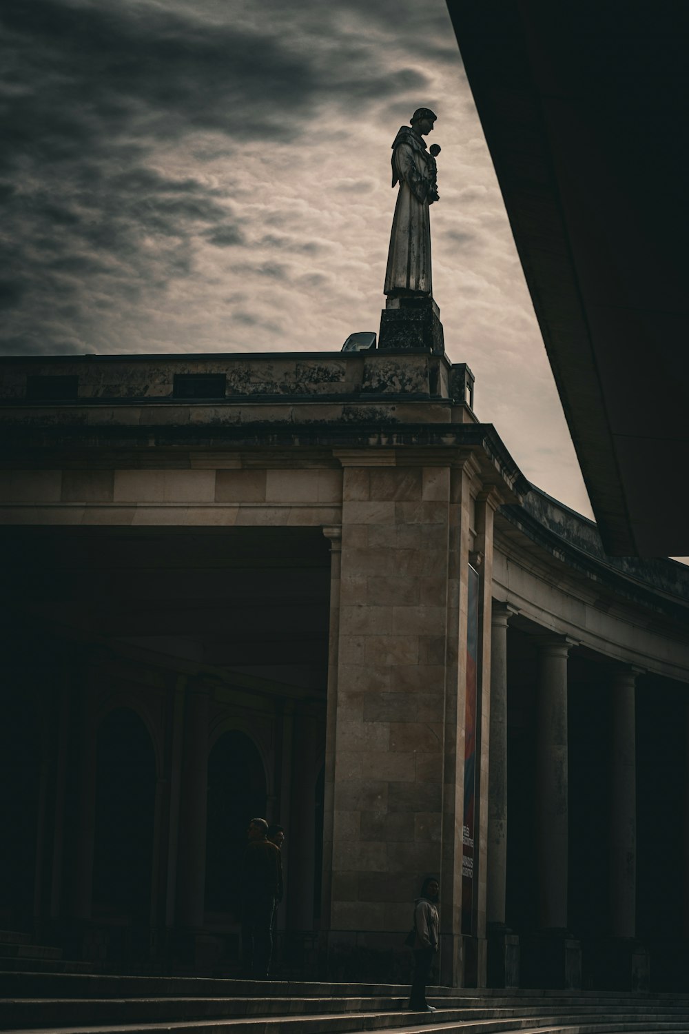 a statue on top of a building under a cloudy sky