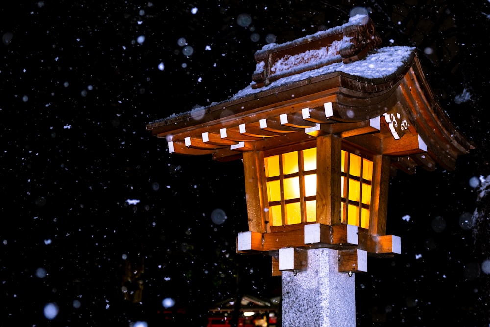 a lit up lantern in the snow at night