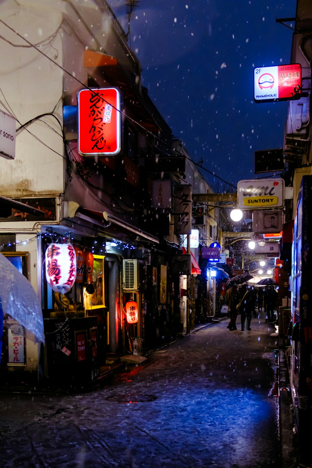 a city street at night with snow falling on the ground