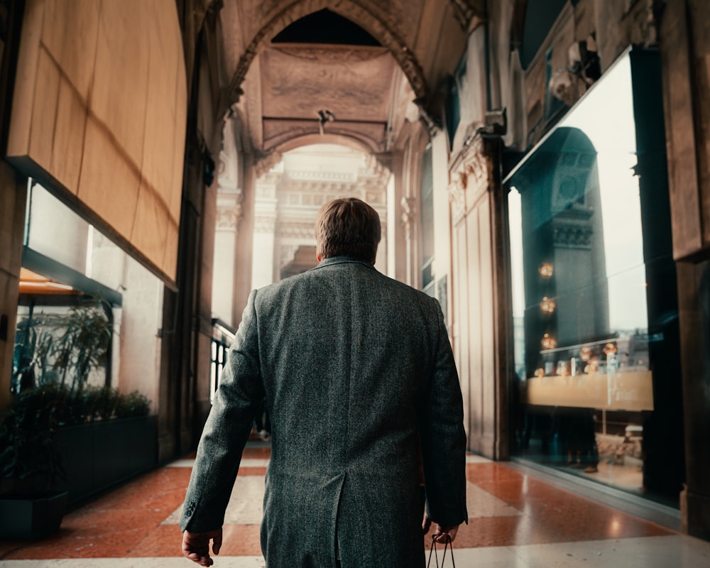 a man in a suit walking down a hallway