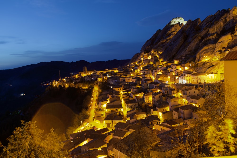 a village is lit up at night in the mountains