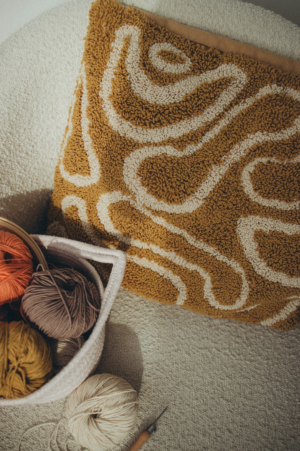 a basket filled with balls of yarn next to a pillow