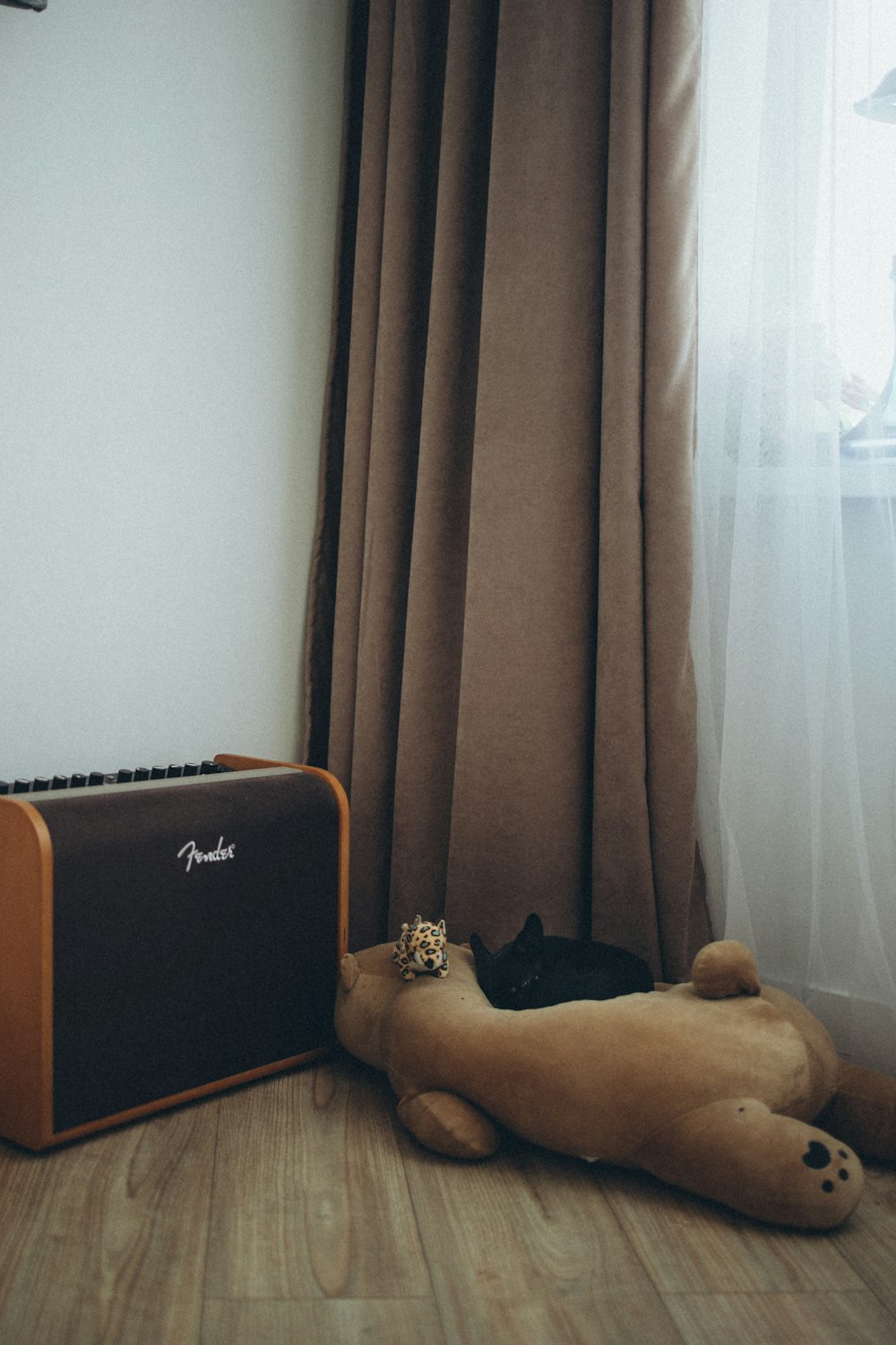 a teddy bear laying on the floor next to a guitar