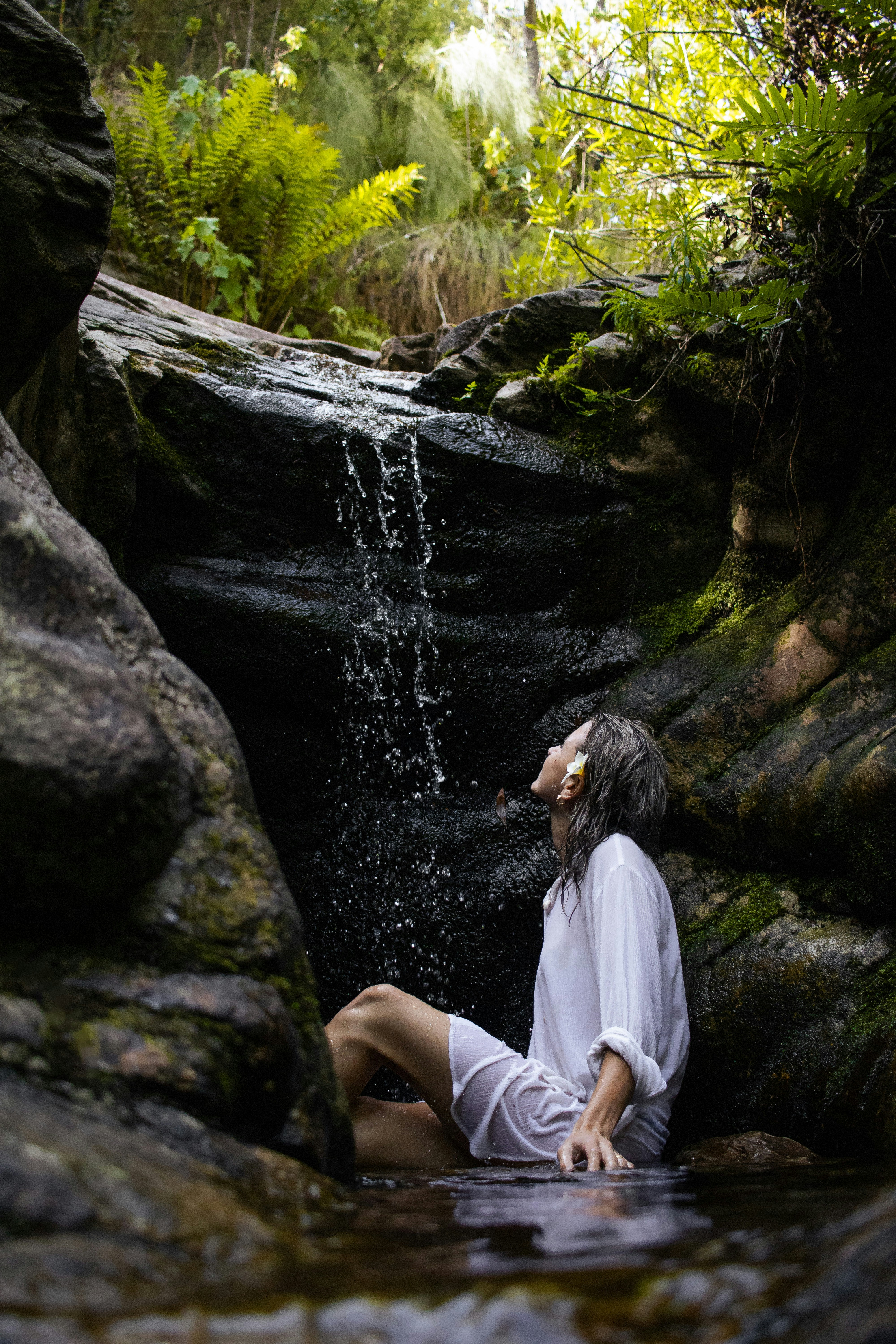 A woman sitting on a rock in the water photo – Free Portrait Image on ...