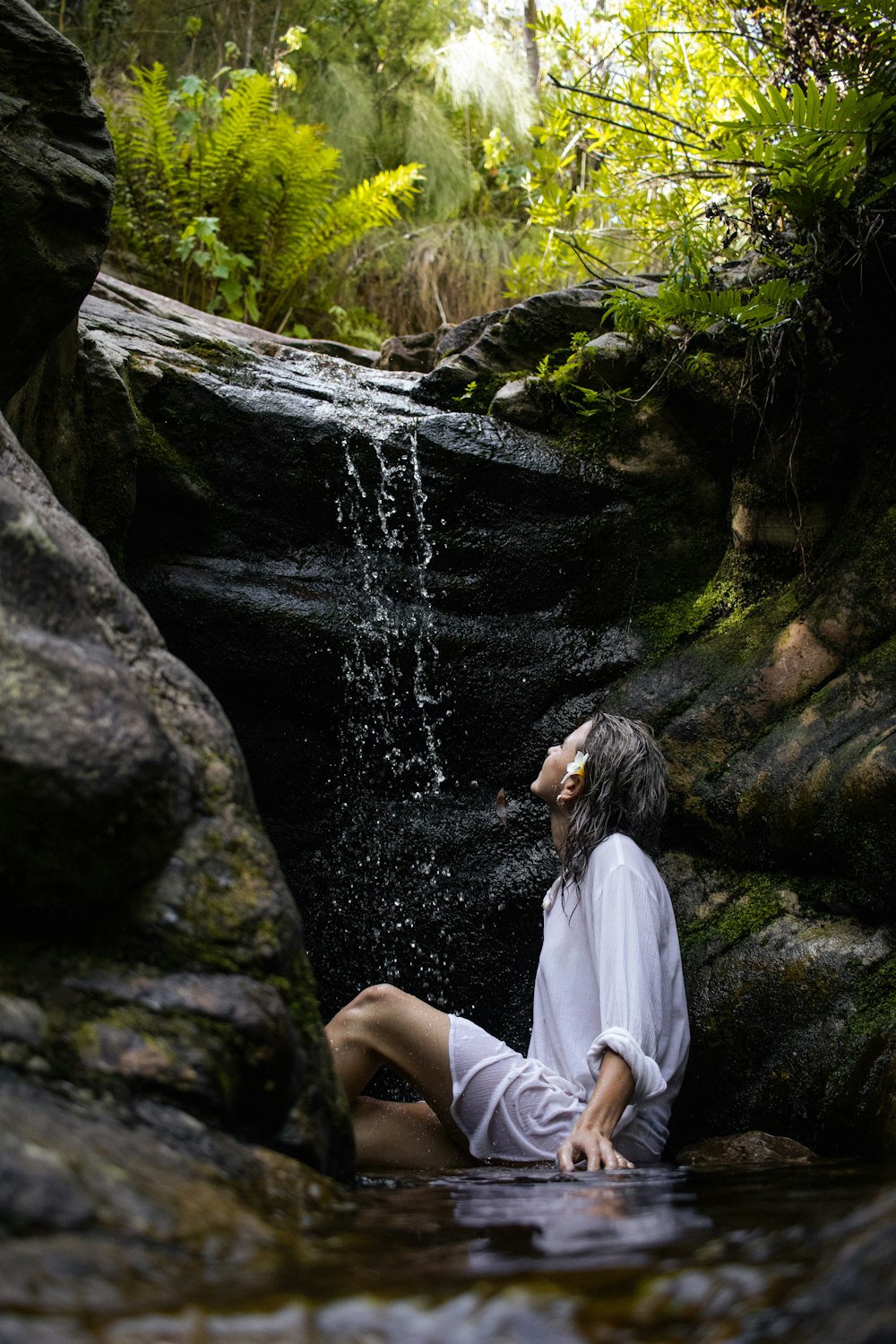 a woman sitting on a rock in the water