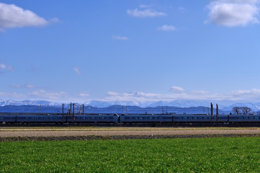 a train traveling down tracks next to a lush green field