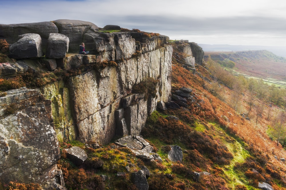 a rocky cliff with grass and rocks on the side