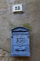 a blue mailbox mounted to the side of a building