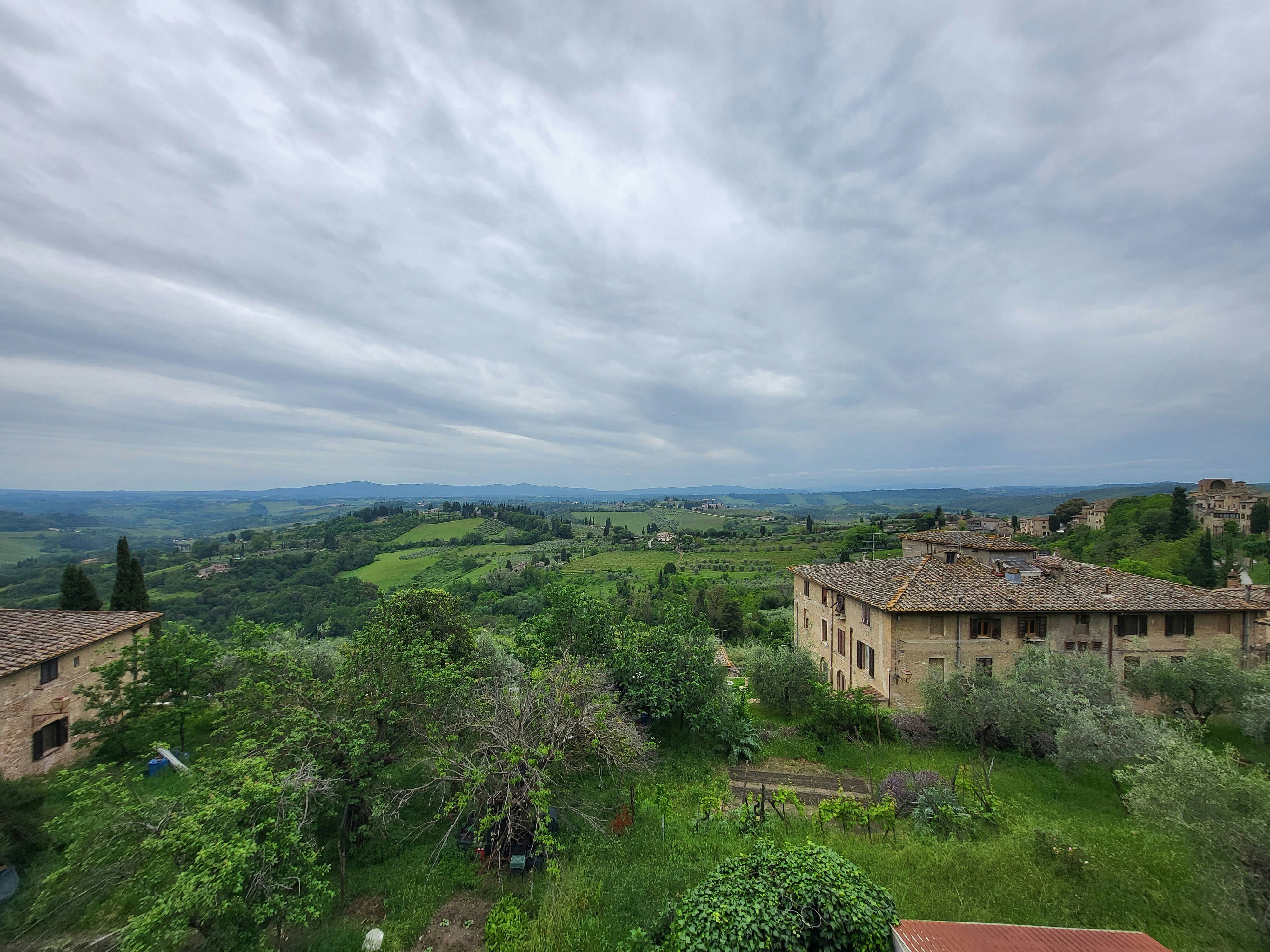 Colline verdi con vigneti e costruzioni in pietra sotto un cielo coperto.
