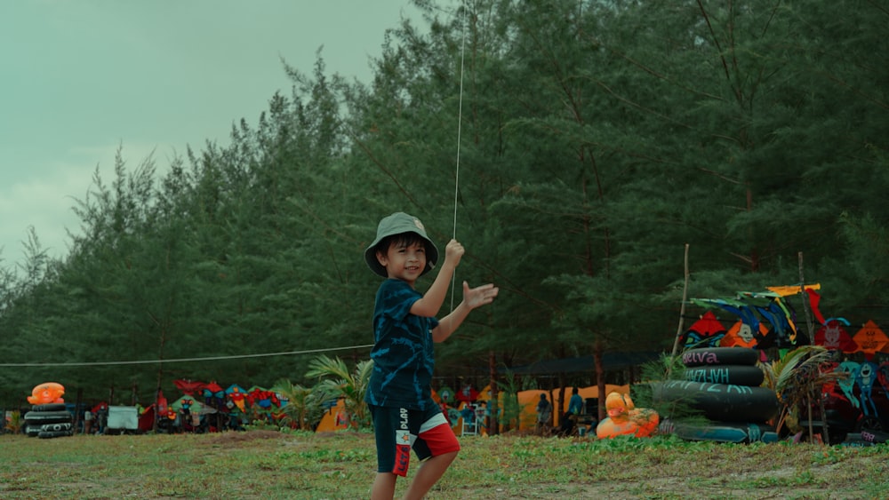 a young boy standing on top of a lush green field