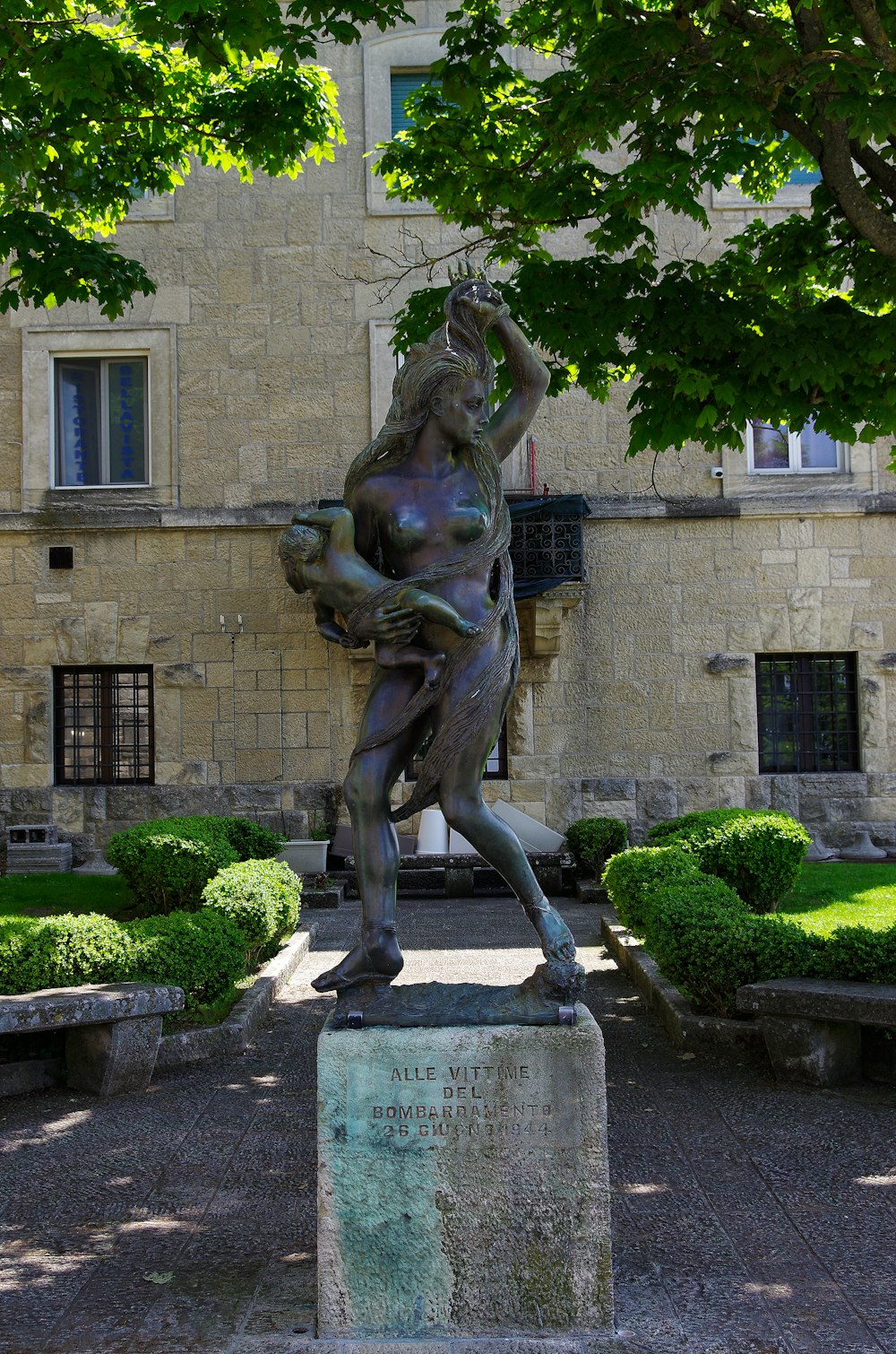 uma estátua de um homem segurando uma planta na frente de um edifício