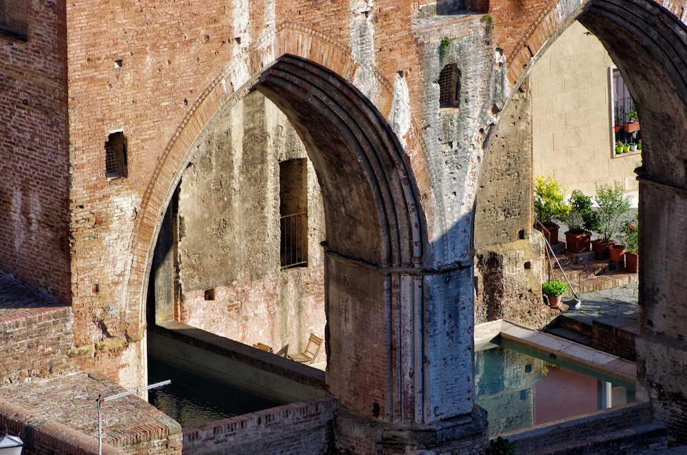 an old brick building with arched doorways next to a canal