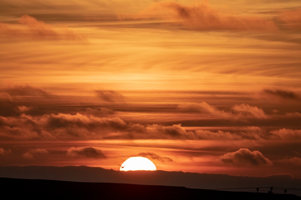 the sun is setting over the horizon of a field