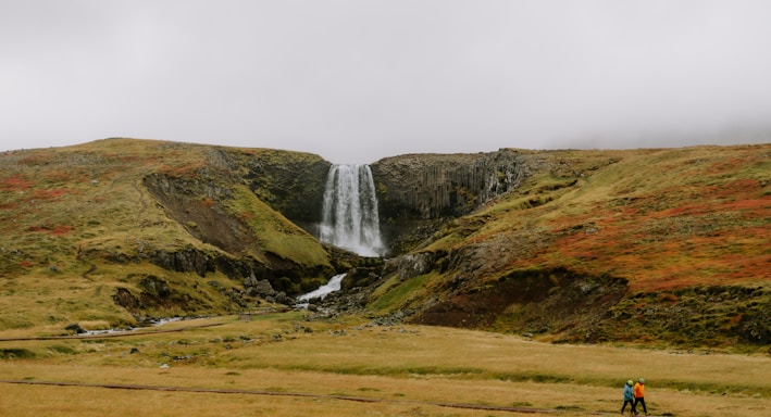 a man standing in front of a waterfall