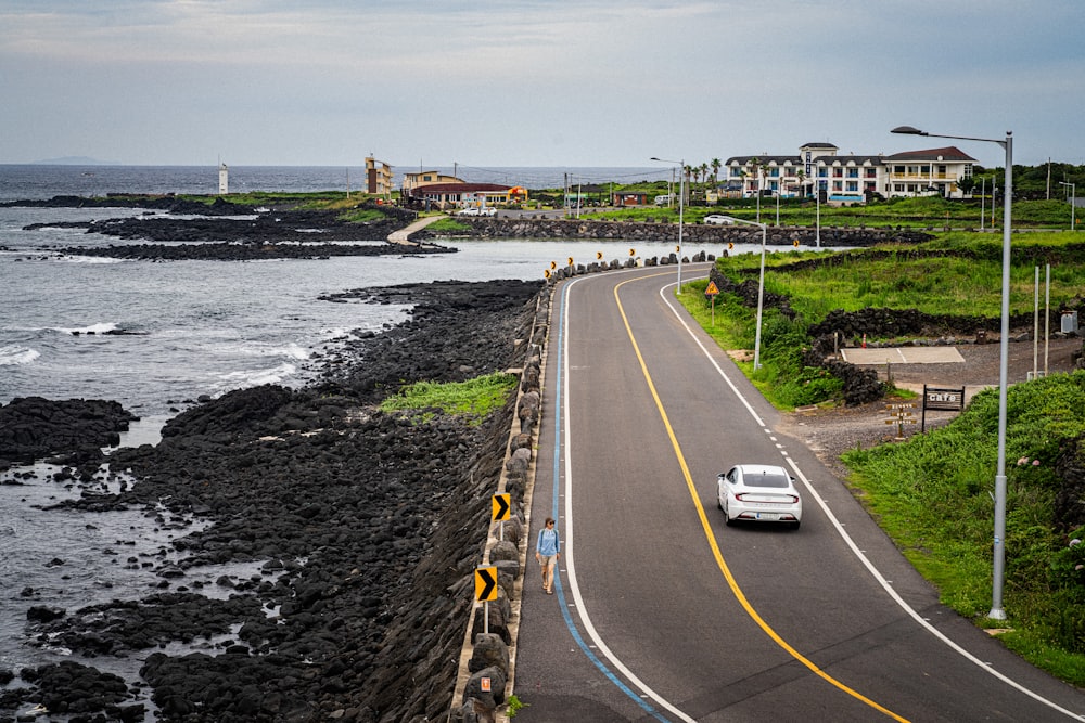 a car driving down a road next to the ocean