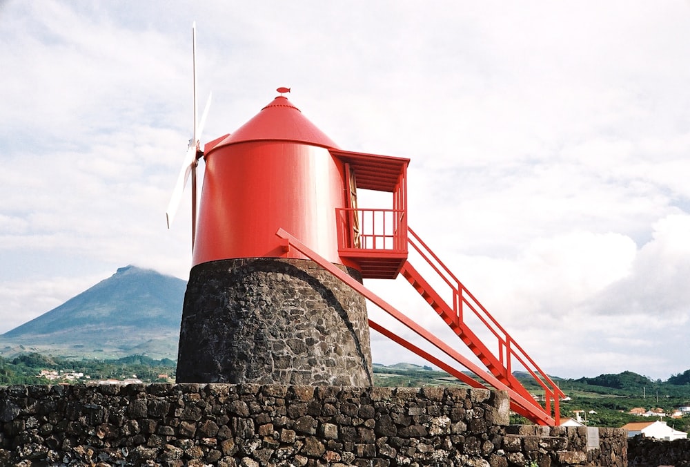 una torre roja sentada en lo alto de un muro de piedra
