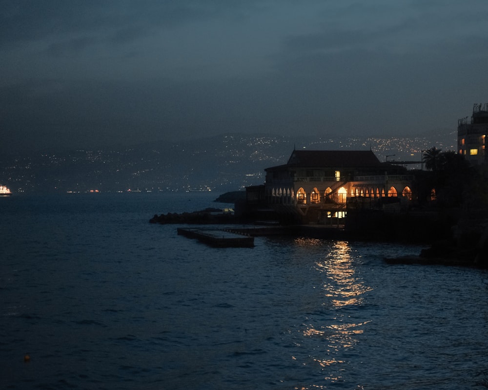 a house is lit up at night by the water