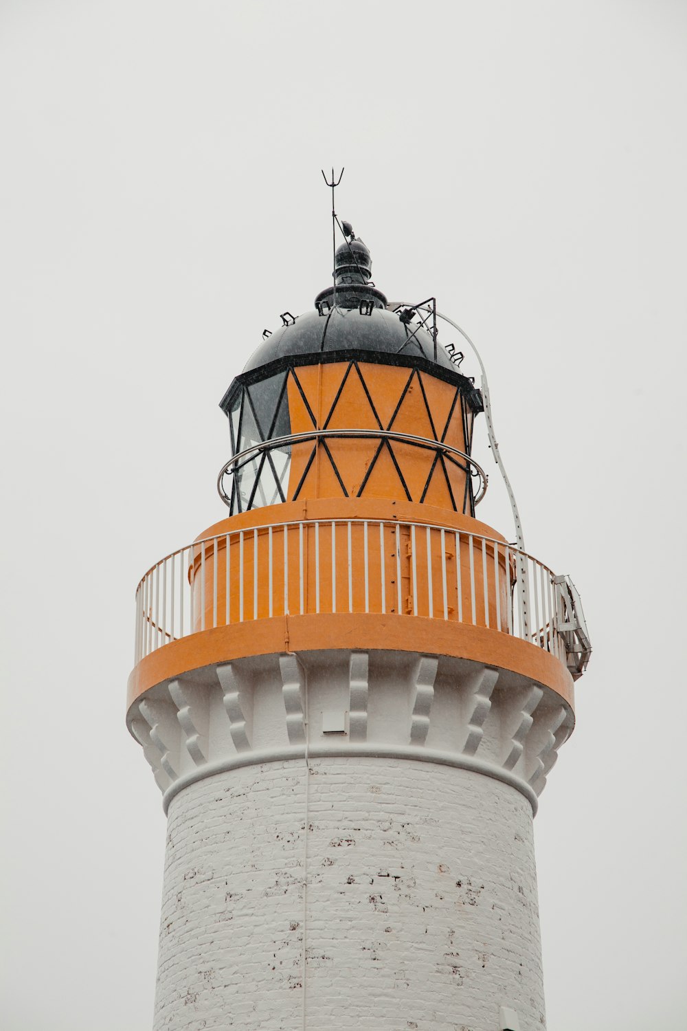 an orange and white lighthouse on a foggy day