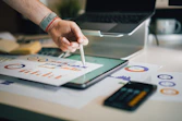 person using stylus on tablet with charts