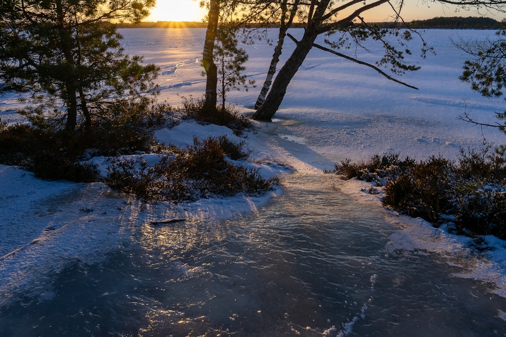 the sun is setting over a frozen lake