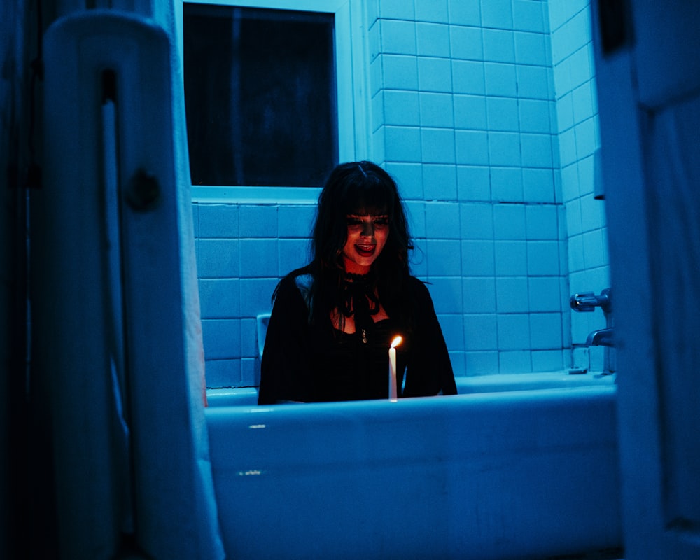 a woman sitting in a bathtub with a lit candle