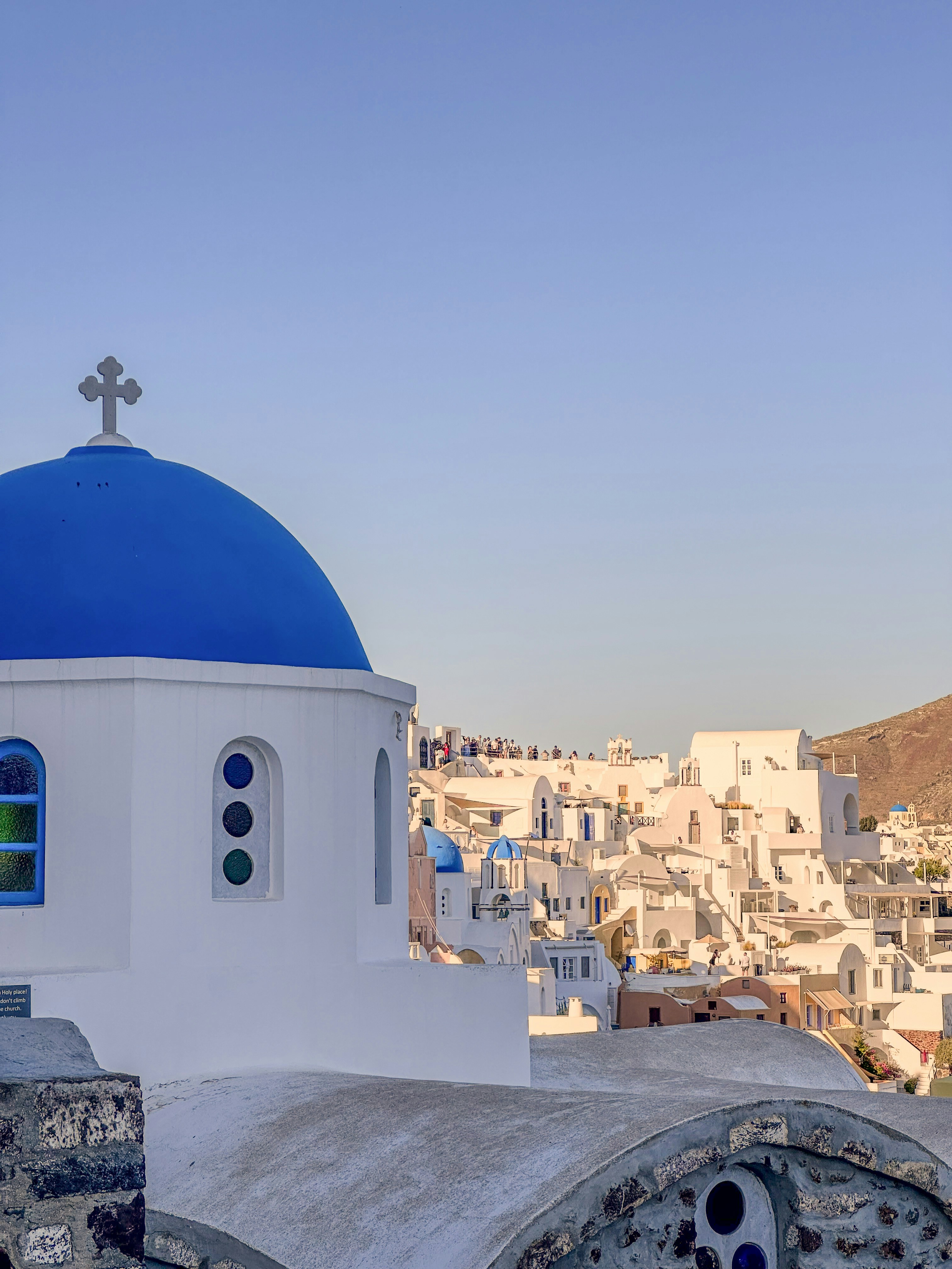 Santorini blue dome church with caldera view, white architecture, bright Mediterranean sunshine