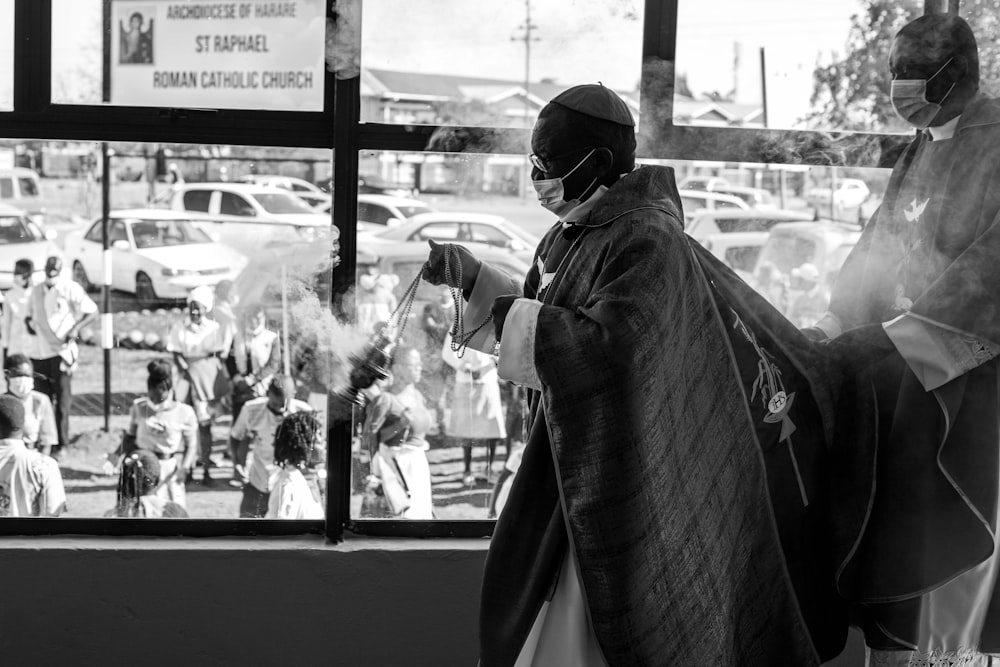 마스크를 쓴 남자가 창문 앞에 서 있다