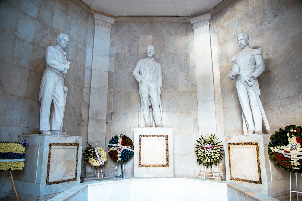 a group of statues in a room with wreaths