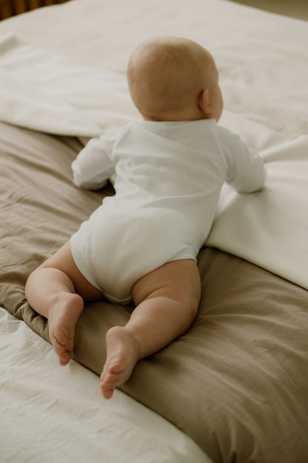 a baby laying on top of a bed on a pillow