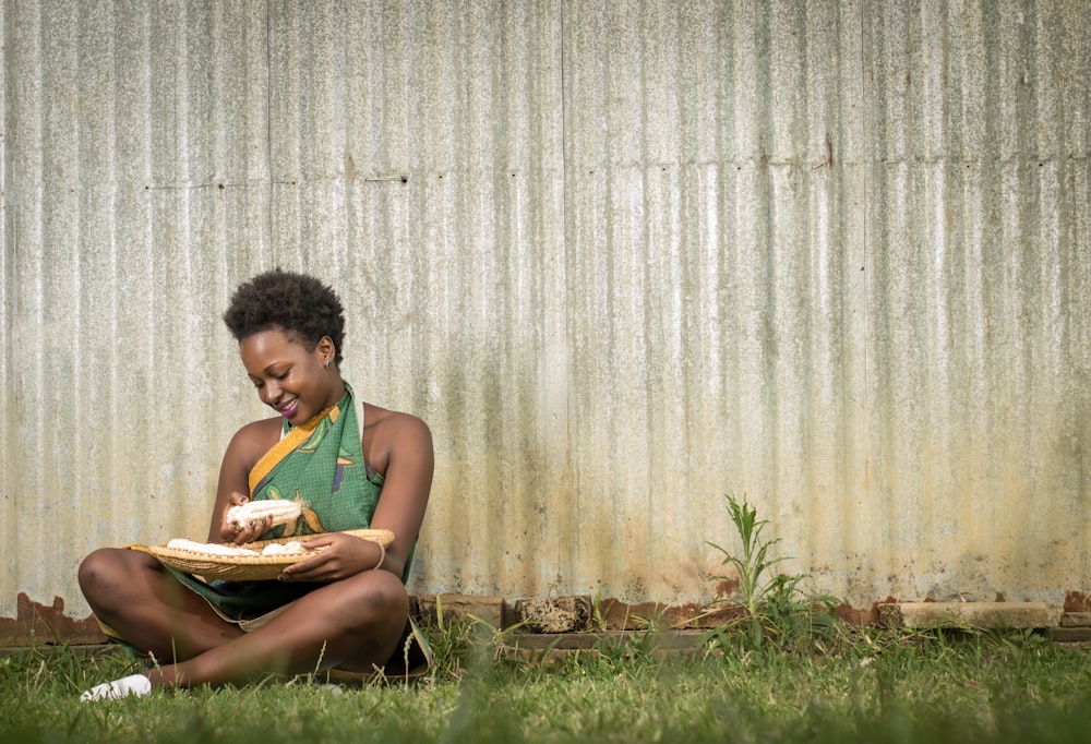 a woman sitting in the grass holding a pizza