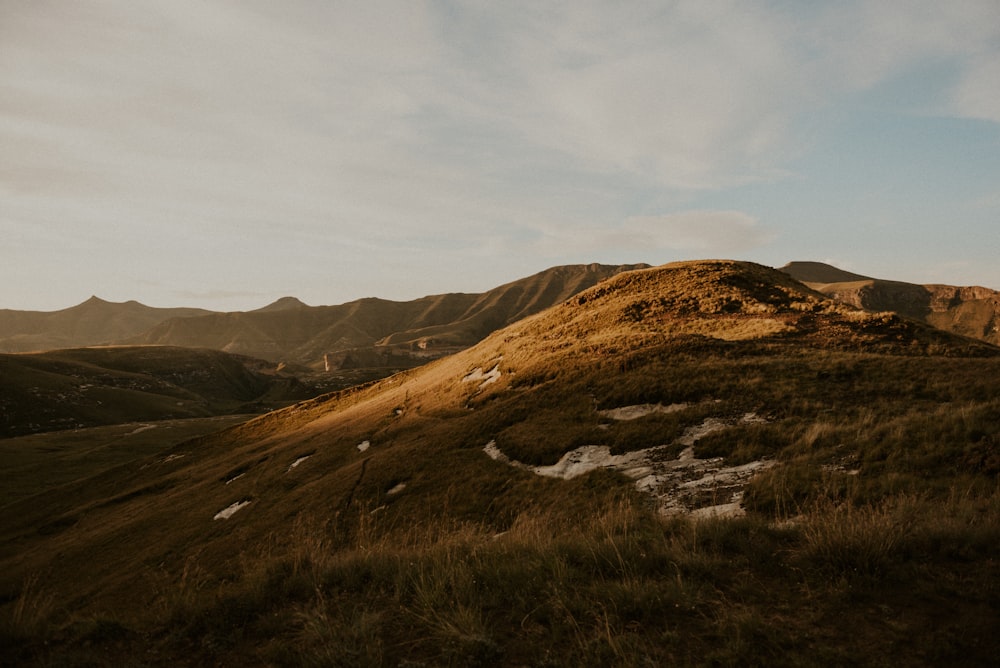 a grassy hill with mountains in the background