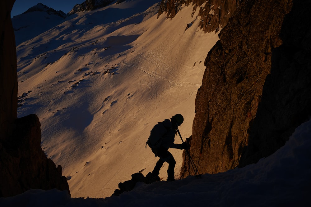 a man climbing up the side of a snow covered mountain