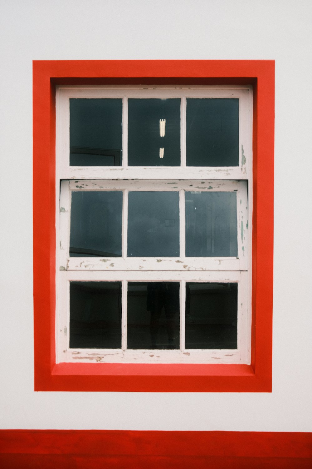 una ventana roja y blanca sobre una pared blanca