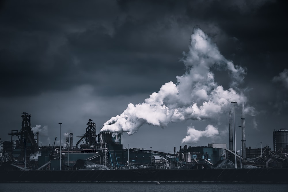 a black and white photo of a factory with smoke stacks