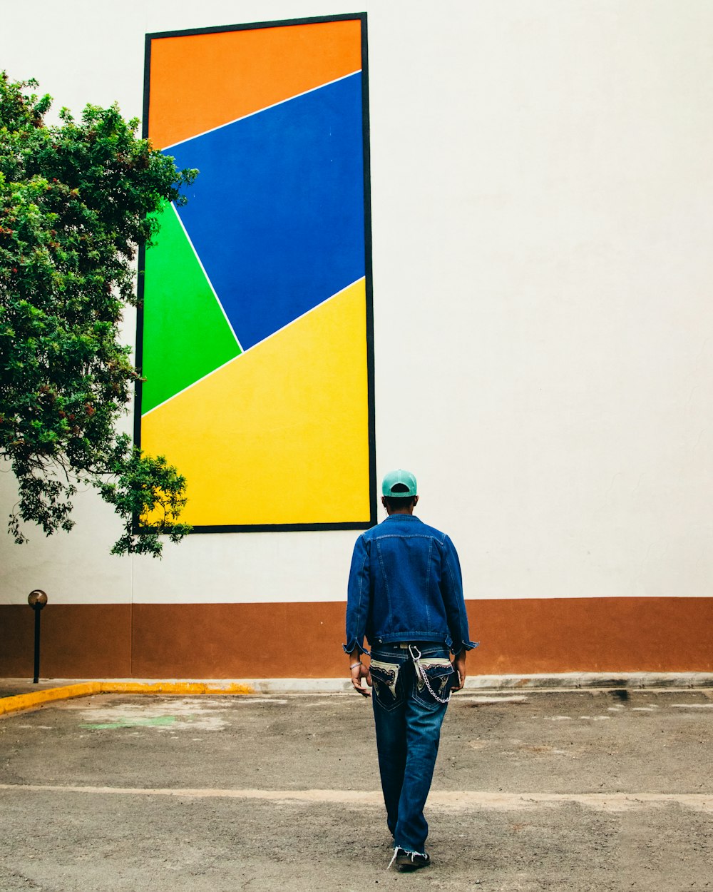 a man walking down a street past a large painting