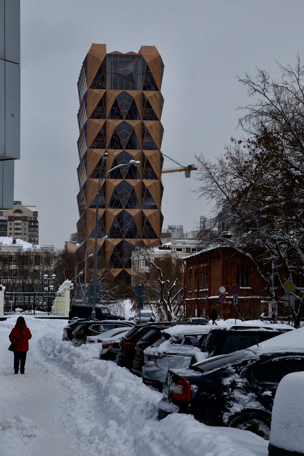 a woman walking down a snow covered sidewalk next to a tall building
