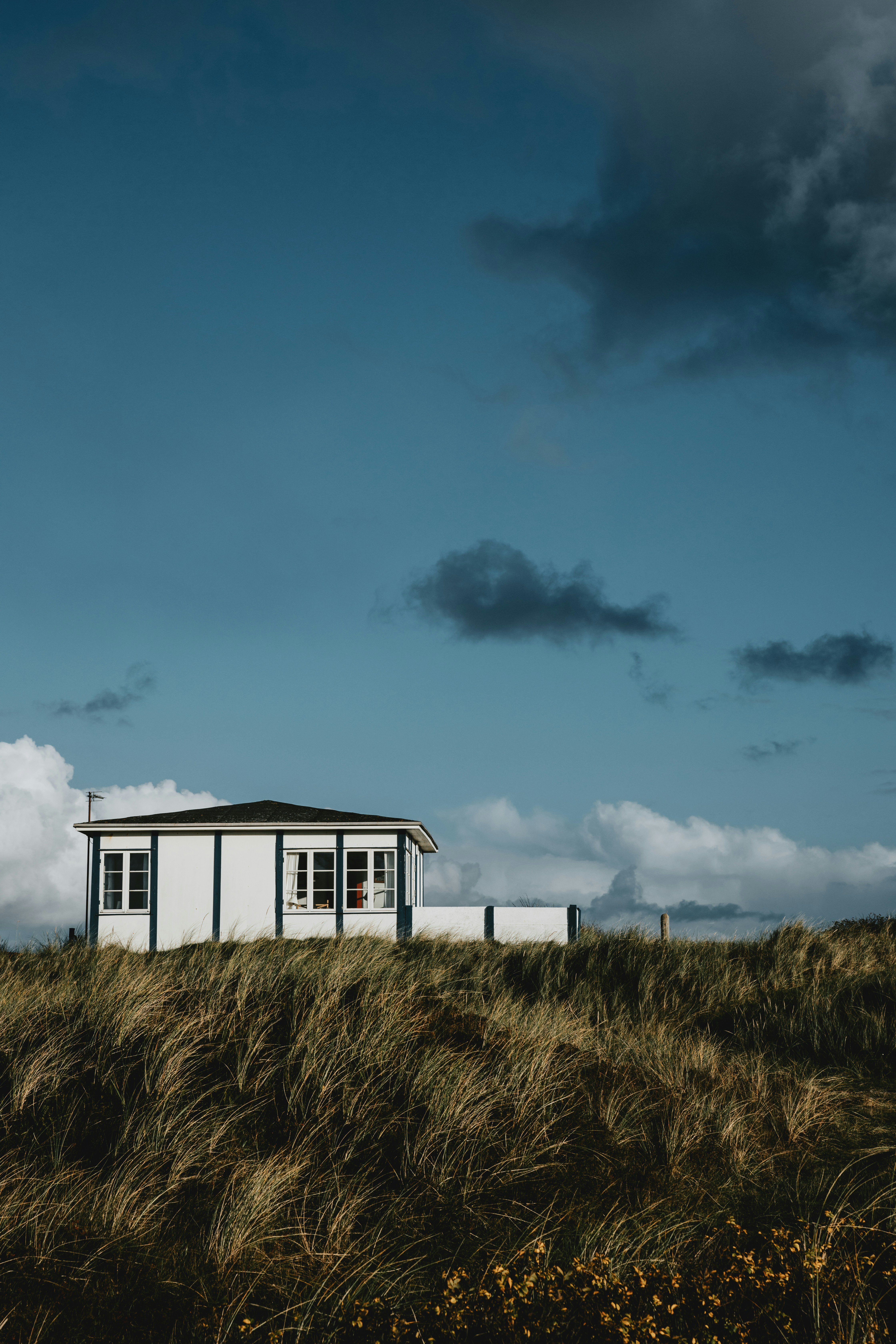 a small white building sitting on top of a grass covered hill