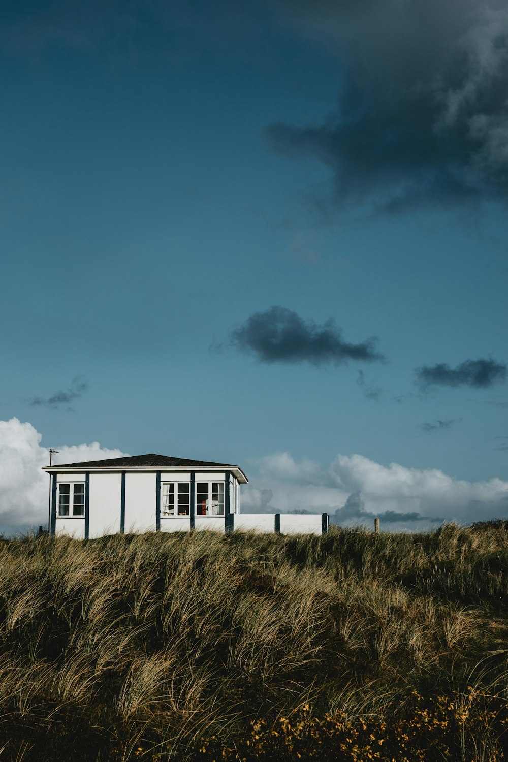 a small white building sitting on top of a grass covered hill