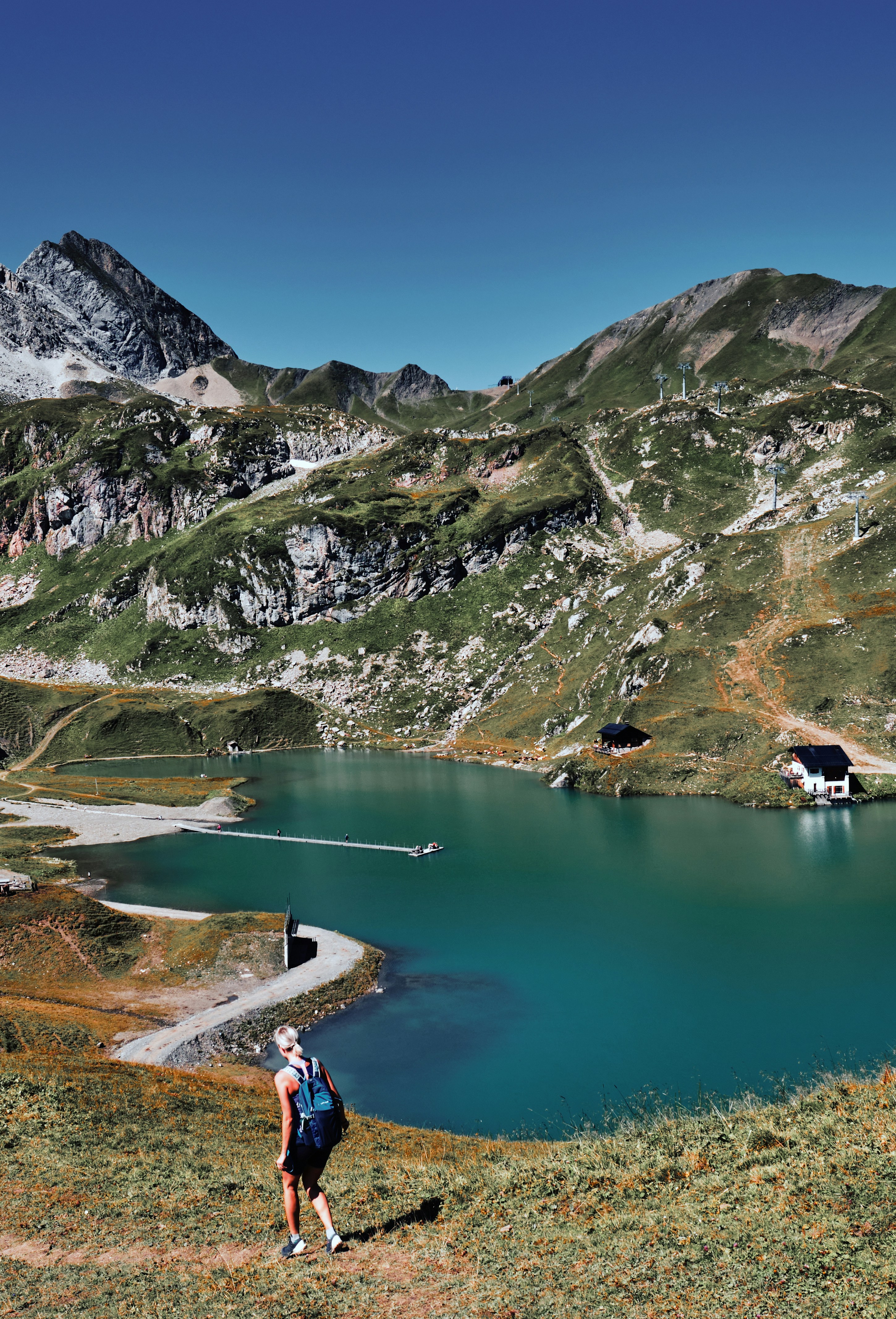 a person with a backpack standing on a hill looking at a lake